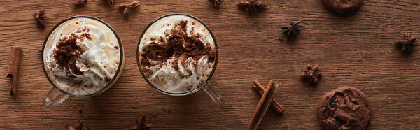 top view of Christmas cacao with whipped cream on wooden table near cookies and spices, panoramic shot