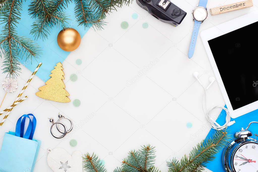 digital camera, champagne bottle, chrismas baubles, fir branch, wristwatch, blue paper, wooden block with december inscription, gift bag isolated on white
