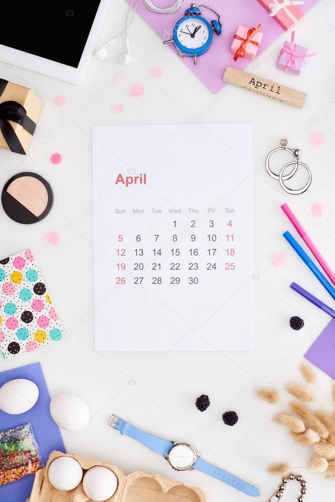 april calendar page, digital tablet, easter decorations, chicken eggs, cosmetics, blackberry, spikelets, wristwatch, wooden block with april inscription isolated on white