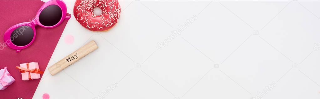 panoramic shot of wooden block with may inscription, donut, sunglasses, gift boxes, crimson paper isolated on white