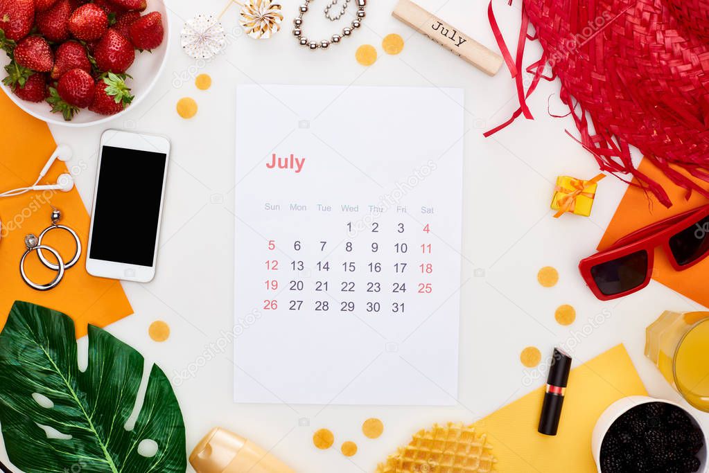 july calendar page, wooden block with july inscription, smartphone, sunglasses, orange juice, fresh strawberry, waffles, cosmetics, earphones, lollipops isolated on white
