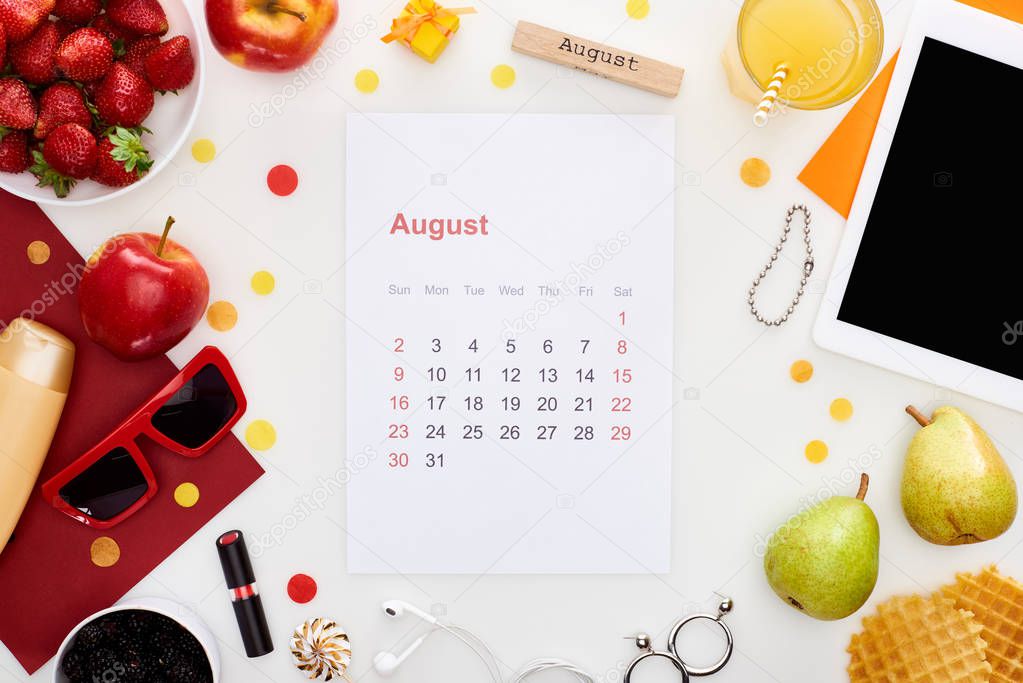 august calendar page, wooden block with august inscription, digital tablet, sunglasses, orange juice, fruits, waffles, cosmetics, earphones isolated on white