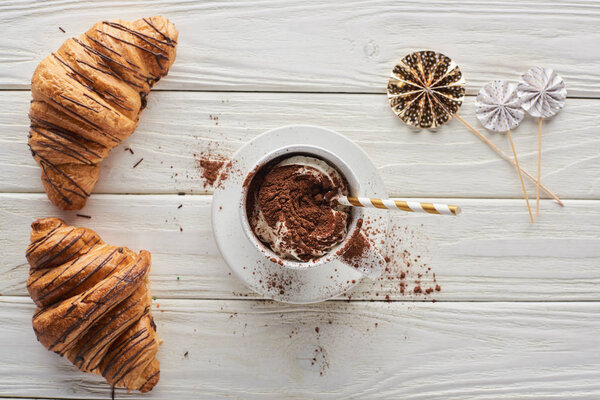 top view of Christmas cacao in mug with decoration near croissants on white wooden table