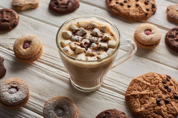 cacao with marshmallow in mug near cookies on white wooden table
