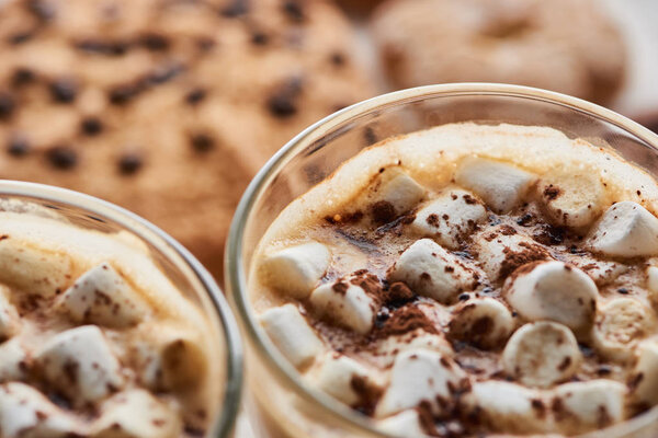 selective focus of cacao with marshmallow in mugs near cookies on white wooden table
