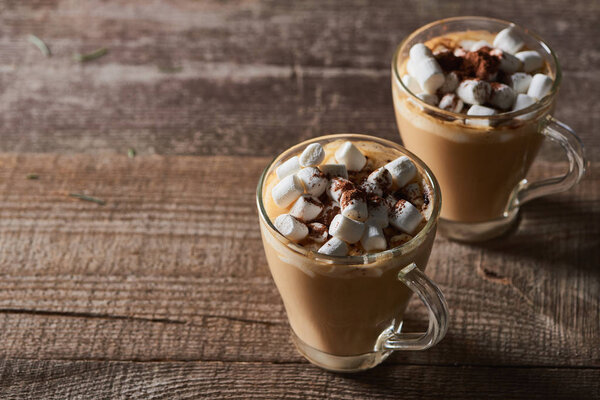 cacao with marshmallow and cacao powder in mugs on wooden table
