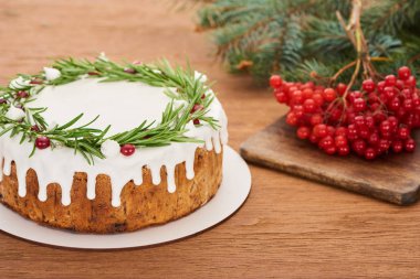 Biberiyeli noel pastası ve ladin dallı ahşap masada viburnum üzümü.