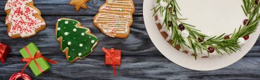 Koyu ahşap masada biberiyeli noel pastası ve küçük hediyeler ve kurabiyeler.