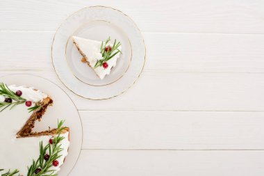 Beyaz ahşap masada kremalı, biberiyeli ve kızılcıklı noel pastası. 