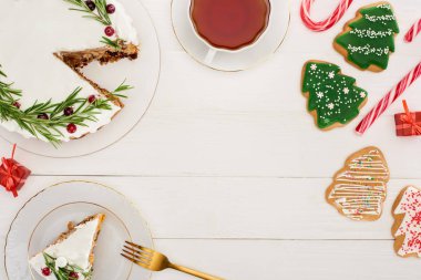 Biberiyeli noel pastası, bir fincan çay ve beyaz ahşap masada noel ağacı kurabiyeleri.