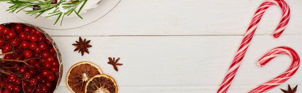 top view of viburnum berries, christmas pie and candy canes on white wooden table 