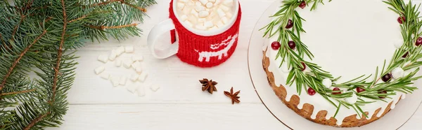 在白色的木制桌子上 有一杯带有棉花糖和云杉枝条的可可 上面是圣诞派的全景 — 图库照片
