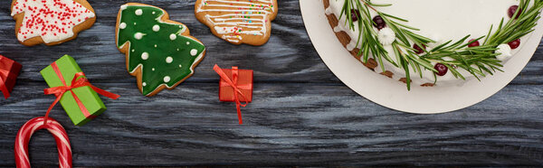сверху вид на рождественский пирог, маленькие подарки и печенье на темном деревянном столе
 