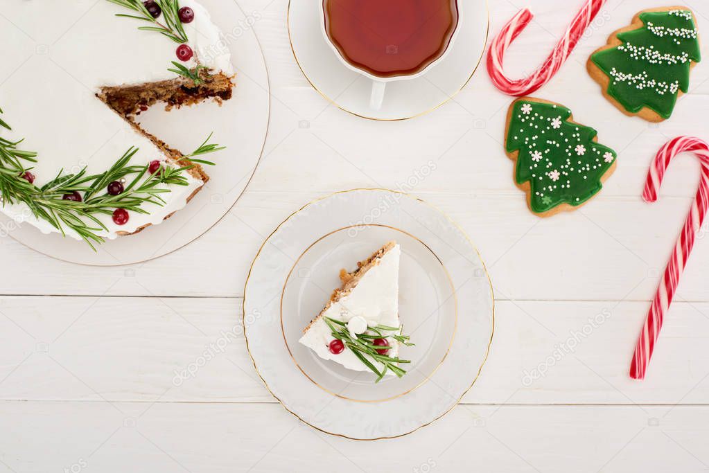 top view of christmas pie, cup of tea, candy canes and cookies on white wooden table