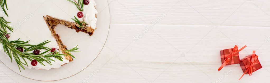 top view of christmas pie with rosemary and cranberries on white wooden table with little gifts