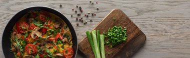 Lezzetli ev yapımı omlet, tavada ve masada malzemeler var.