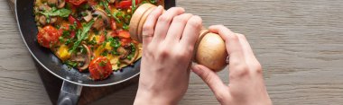 Omlete biber serpiştiren mantarlı, domatesli ve tavada yeşillik serpiştiren kadın manzarası 