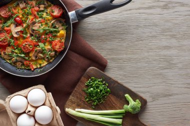 Lezzetli ev yapımı omlet ve ahşap masa malzemeleri.
