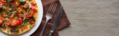 Tahta masa üzerinde çatal, bıçak ve peçeteyle ev yapımı omlet manzarası