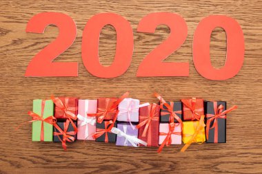 Kağıt 2020 rakamlarının üst görünümü küçük dekoratif hediye kutularının yanında ahşap arka planda