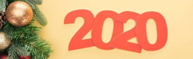 2020 sayılı kağıdın en üst görüntüsü noel ağacı dalının yanında sarı arka planda mücevherler, panoramik çekim