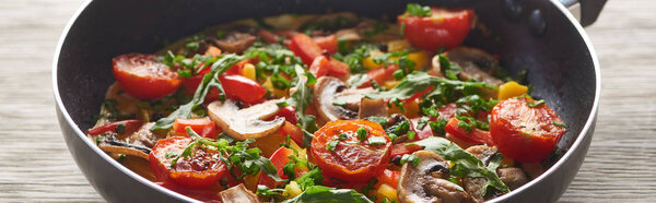 крупным планом вкусный омлет с грибами, помидорами и зеленью в сковороде
