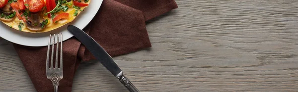 用叉子 小刀和餐巾在木制桌子上的自制煎蛋卷的顶部视图 — 图库照片
