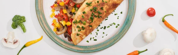 top view of plate with yummy wrapped omelet with vegetables on white table with ingredients 