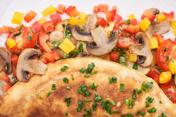 close up of homemade wrapped omelet with mushrooms and peppers