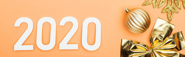 top view of white 2020 numbers near golden christmas decoration on orange background, panoramic shot