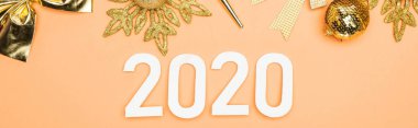 Turuncu arka planda altın noel süslemesi yakınlarındaki beyaz 2020 rakamlarının üst görünümü, panoramik çekim