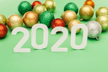 Beyaz 2020 rakamları yeşil arka planda çok renkli Noel mücevherleri