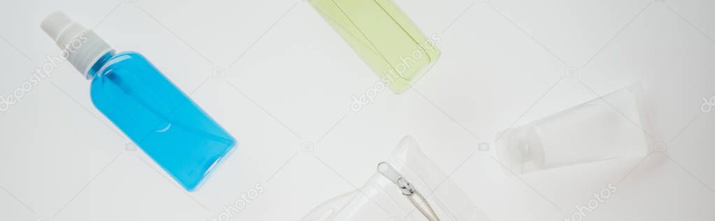 panoramic shot of cosmetic bag and bottles with liquids on white background 
