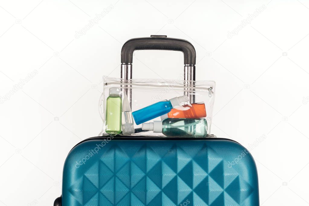 travel bag with cosmetic bag with colorful bottles with liquids isolated on white