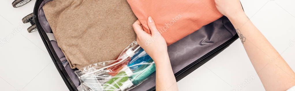 panoramic shot of woman packing travel bag on white background 