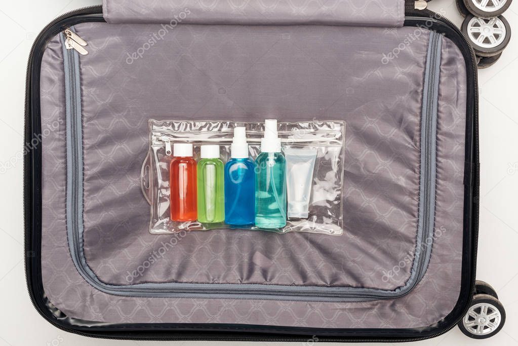 top view of transparent cosmetic bag with colorful bottles on travel bag 