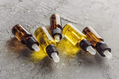 Gri taş yüzeydeki köknar dallarının yanında doğal serum bulunan şişeler.