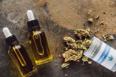 top view of medical marijuana buds near container and bottles with hemp oil on marble surface clipart