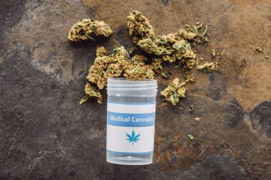 Mermer yüzeydeki konteynır yakınındaki tıbbi marihuana tomurcuklarının üst görüntüsü
