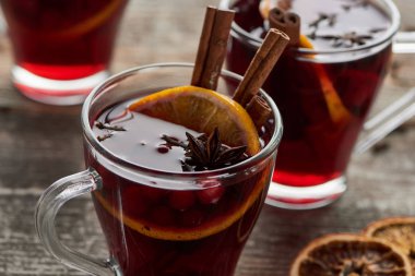 close up view of red spiced mulled wine with berries, anise, orange slice and cinnamon on wooden rustic table clipart