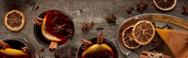 top view of red spiced mulled wine with berries, anise, orange slices and cinnamon on wooden table, panorama shot