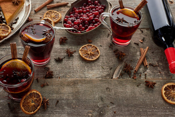 red spiced mulled wine near berries, anise, orange slices and cinnamon on wooden rustic table with copy space