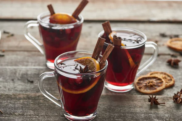 hot red spiced mulled wine with berries, anise, orange slice and cinnamon on wooden rustic table