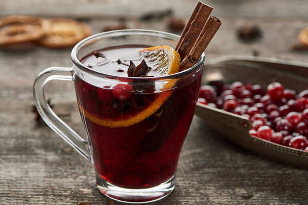 red spiced mulled wine with berries, anise, orange slice and cinnamon on wooden rustic table