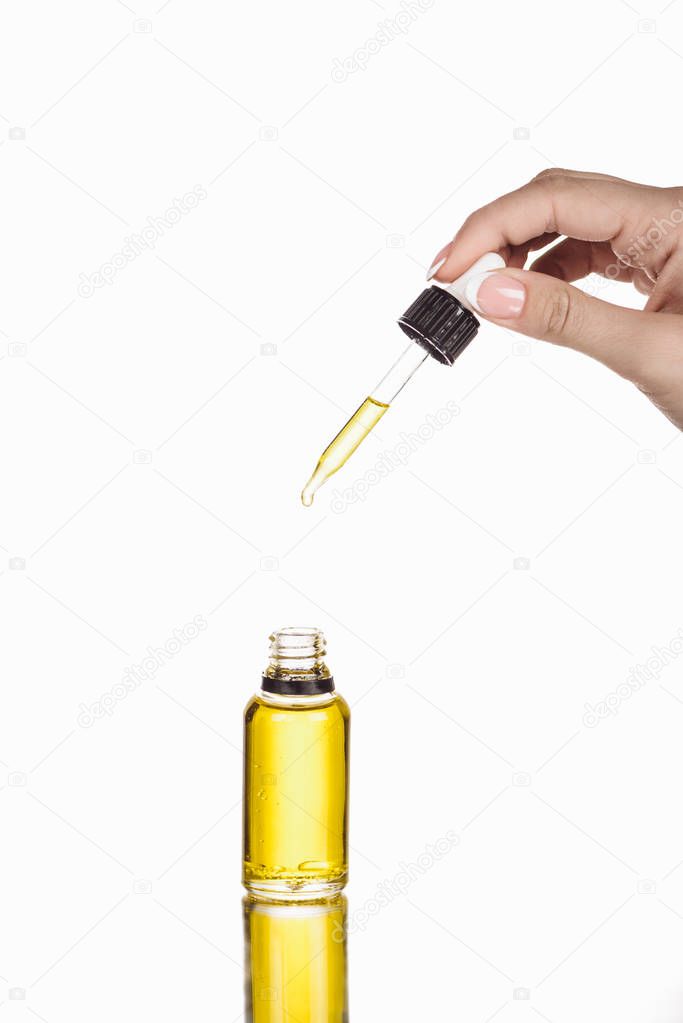 cropped view of woman holding dropper near bottle with natural serum isolated on white