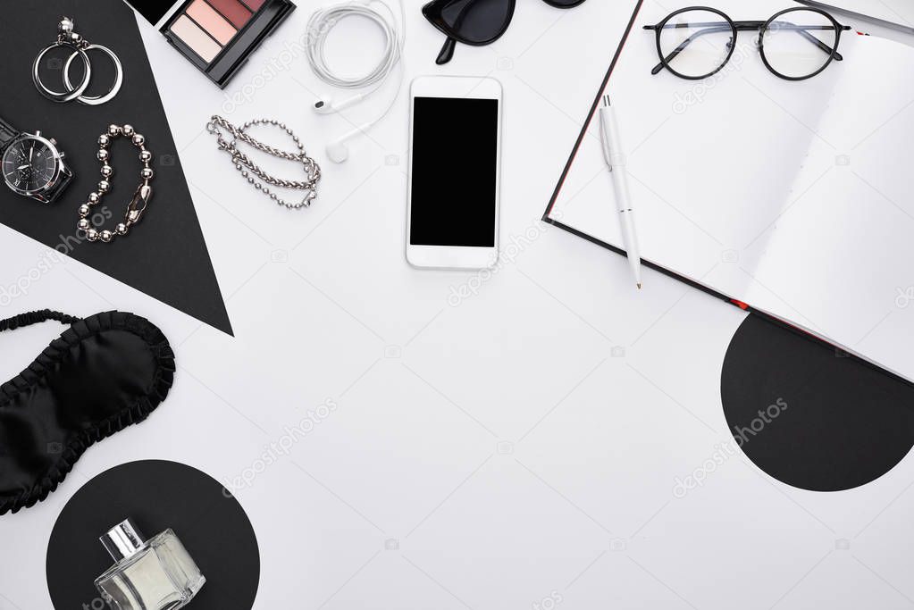 top view of gadget, perfume, bracelets, decorative cosmetics, sleeping mask, earphones, glasses, notebook, earrings