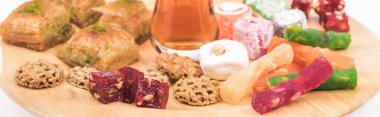 wooden board with delicious turkish sweets and tea isolated on white, panoramic shot clipart