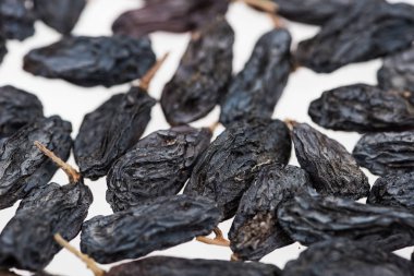 Beyaz üzerine izole edilmiş siyah kuru üzümlerin yakın görüntüsü