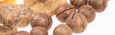 Beyaz panoramik karede izole edilmiş kurutulmuş mango dilimleri, incir ve macadamia fındıkları.