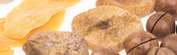 close up view of dried mango slices, figs and macadamia nuts isolated on white, panoramic shot